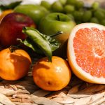 Vibrant assortment of fresh fruit including citrus and apples placed in a natural setting.